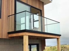 a balcony with glass railings and wood siding on the side of a house in australia