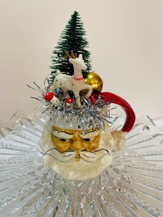 a glass figurine with a christmas tree on it's head in front of a white background