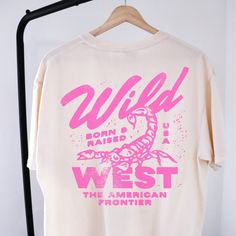 🤠Embrace the spirit of the Wild West with our "Wild West Born & Raised" graphic tee! This vintage-inspired shirt features a bold pink design that pays homage to the rugged American frontier. Perfect for your country concert or your night out in Nashville! 🔥 Stand Out in Style: Whether you're hitting the rodeo or just hanging out with friends, this graphic tee is sure to turn heads and start conversations. Pair it with your favorite jeans or shorts for a casual yet cool look that's perfect for any occasion.  🖤SHIRT MATERIAL Comfort Colors Unisex Shirt 100% Ring-Spun Cotton Printed using Direct To Garment style- Inks are printed directly into the fabric. Different sizing may effect placement of final design. Colors may differ slightly due to different user monitor and screen settings.  🏁 Country Concert Tshirts, Retro Graphic Shirt, Female Graphic Tees, One Color T Shirt Designs, Concert T Shirt Design, Concert Tee Design, Trendy Oversized T Shirts, Fun Shirt Designs, Wild West Design