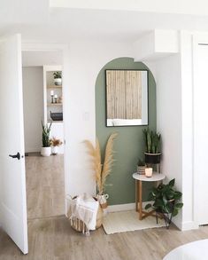 a living room filled with lots of furniture next to a wall mounted mirror and potted plants