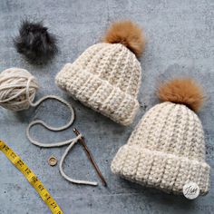 two crocheted hats with yarn and scissors next to them