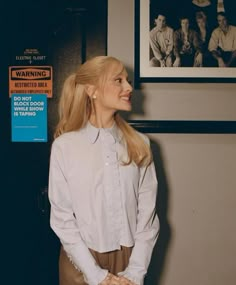 a woman standing in front of a wall with pictures on it