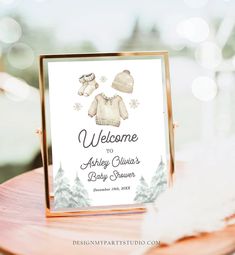 a welcome sign for a baby shower is displayed on a wooden table with snowflakes