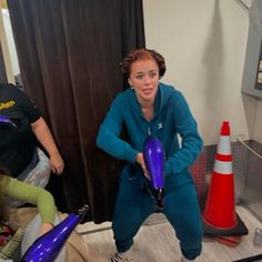 a woman holding a purple blow dryer in her hands while standing next to another woman