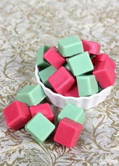 a bowl filled with pink and green cubes sitting on top of a tablecloth