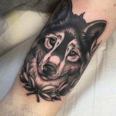 a black and white wolf tattoo on the right arm, with flowers around its neck