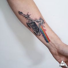 a person holding their arm with a tattoo on it that has a rainbow in the middle