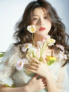 a woman with long hair holding flowers in her hands