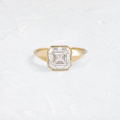 an engagement ring with a square cut diamond in the center, on a white surface