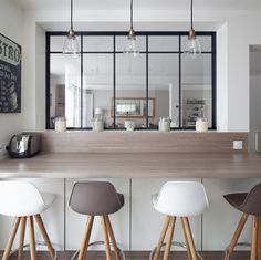 three bar stools sit in front of a counter with a mirror on the wall