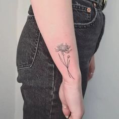 a woman's arm with a small flower tattoo on it