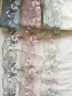 four pieces of fabric with flowers and pearls on the bottom one piece is blue, white, gray and pink