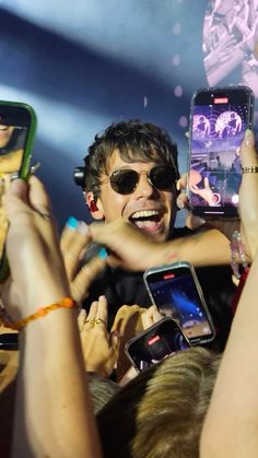 a group of people holding up cell phones in front of each other at a concert