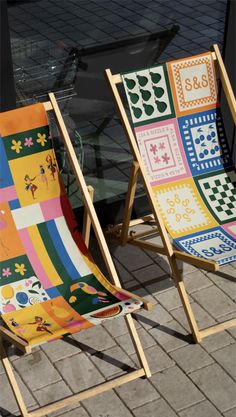 two lawn chairs sitting next to each other on top of a brick floor covered in colorful quilts