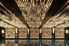 an indoor swimming pool surrounded by lights and wood paneled walls with mirrors on the ceiling