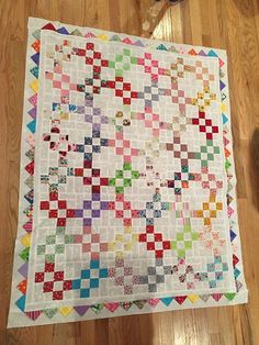 a multicolored quilt sitting on top of a wooden floor next to a pair of scissors