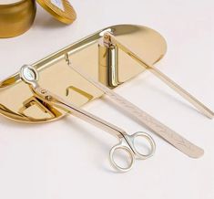 a pair of scissors sitting on top of a gold plate next to some other items