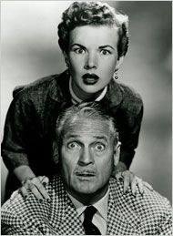 an old black and white photo of a man sitting on top of a woman's head