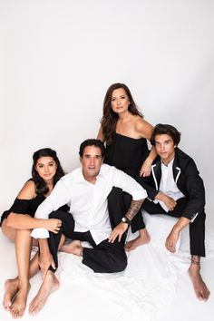 four people posing for the camera in black and white outfits with one woman sitting on the floor