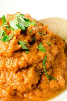 a white plate topped with meat covered in sauce and garnished with parsley