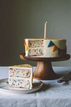 a white cake with sprinkles and a slice missing from it on a plate