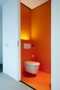 an orange and white bathroom with a toilet in the corner next to it's door