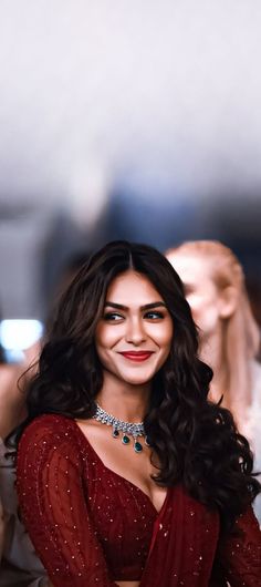 a woman in a red dress smiling and posing for the camera with her hands on her hips