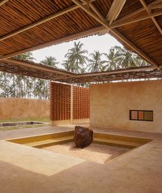 an empty room with a large rock in the center and palm trees in the background