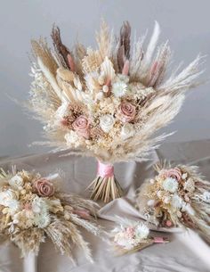 three bouquets with dried flowers and feathers on a tableclothed cloth covered surface