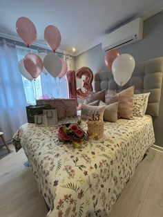 a bed topped with lots of pillows and balloons