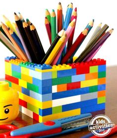 a lego desk organizer with colored pencils in it and a cup full of crayons