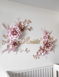 a white crib with pink flowers and butterflies on the wall next to a name sign