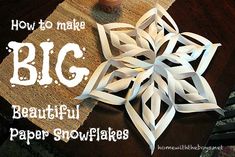 a paper snowflake sitting on top of a wooden table next to a cup