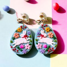 the earrings are decorated with colorful flowers and bunny silhouettes on blue, pink, yellow, green, purple