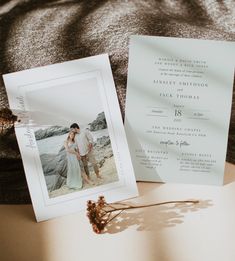 an image of a couple on the beach next to their wedding card and photo frame