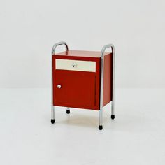 a red and white cabinet sitting on top of a metal frame with handlebars