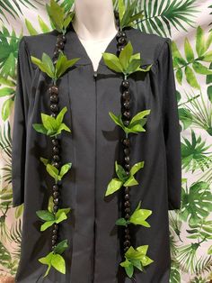 a black graduation gown with green leaves and beads