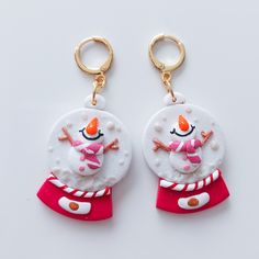 two snowmen wearing red and white outfits are hanging from gold - plated hooks