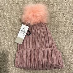 a pink hat with a fur pom