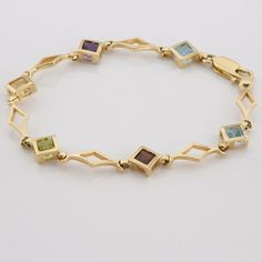 "14K Yellow Gold Multicolor Stone Bracelet, 6 - 6mm square stones, blue topaz, amethyst, citrine, peridot, garnet, blue topaz, or visa versa, triangular links, 7\"x3/8\", Circa 1990, 8.1 grams Stock # BB210B18 This listing contains photographs of the actual item you will receive. Our items are in excellent condition with little or no signs of wear and many are one of a kind pre-owned estate finds. Please look closely at the pictures in this listing as they are part of the product description. Pl Modern Multi-stone Rectangular Jewelry, Rectangular Gemstone Bracelet In Yellow Gold, Gold Rectangular Multi-stone Jewelry, Rectangular Yellow Gold Bracelet With Gemstone, Gem Stone Bracelet, Square Stone, Fine Jewelry Designers, Yellow Gold Earring, Blue Topaz Ring