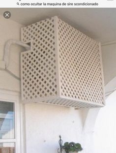 the corner of a white building with a planter on it's side and a window in the background