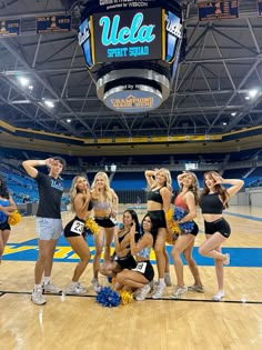 a group of cheerleaders pose for a photo in the middle of a basketball court