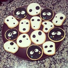 cookies decorated to look like ghost faces on a plate