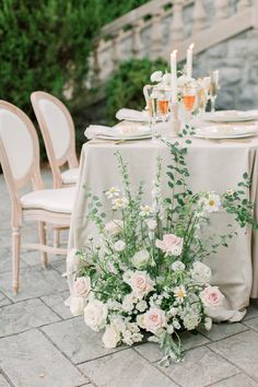 a table set up with flowers and candles for an outdoor wedding reception in the garden