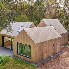 an aerial view of a wooden house in the woods with trees and grass around it