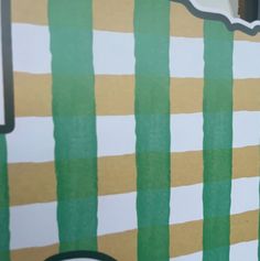 a close up of a clock on a wall with green and yellow striped paper behind it