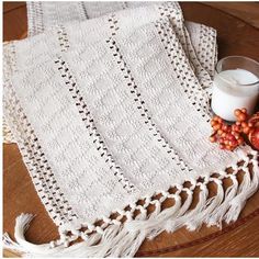 a white crocheted table cloth with tassels and a glass of milk