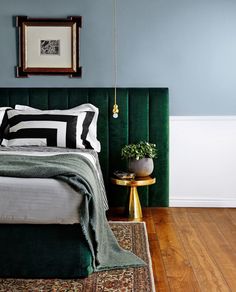 a bedroom with blue walls and green velvet headboard