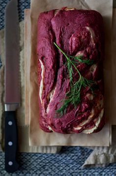 a loaf of beet bread sitting on top of a piece of wax paper next to a knife