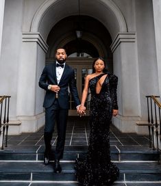 a man in a tuxedo and a woman in a sequin dress holding hands